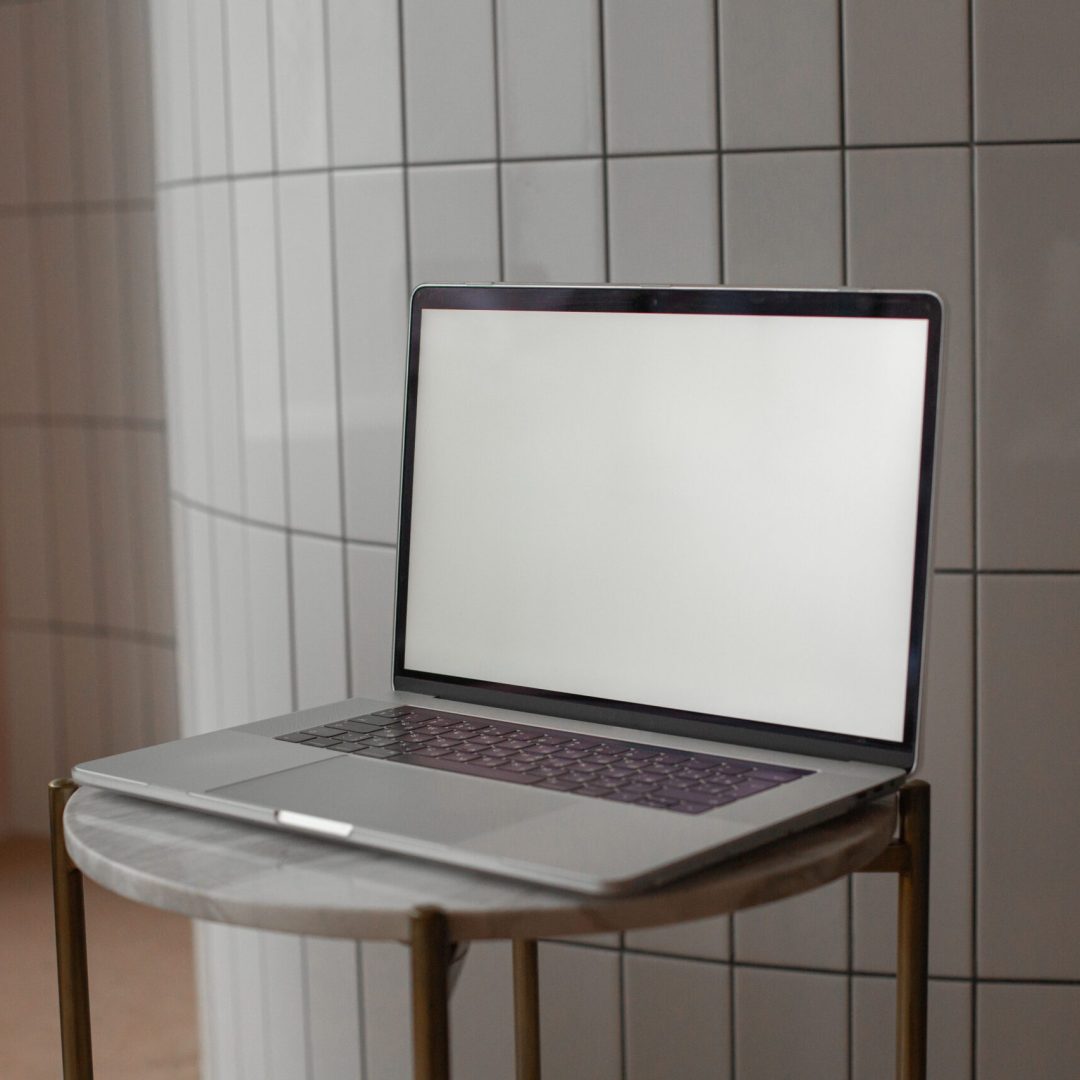 pexels-photo-6372817-6372817 A sleek laptop with a blank screen on a round marble-top table indoors.